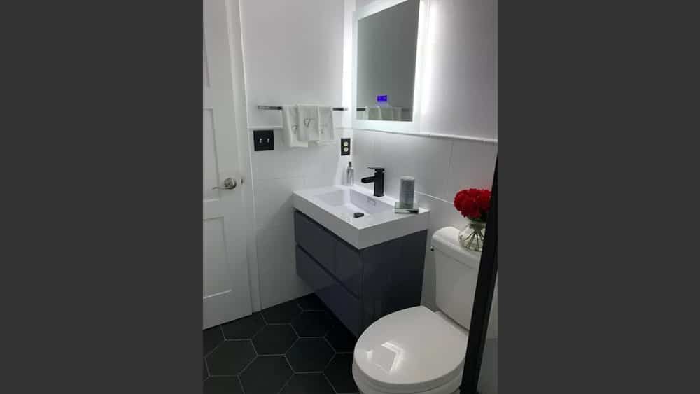 Image of toilet and vanity in a half bath with a grey vanity bottom and white fixtures.