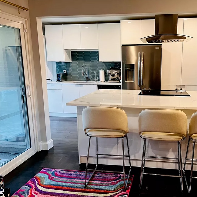 Beautifully remodled kitchen for Kristen P of Danbury Connecticut with modern white marble counter and island tops, a beautiful teal backsplash behind the oven and range combo and a brushed copper refrigerator.