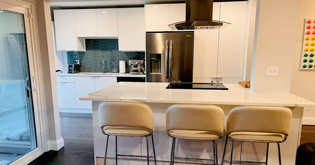 Beautifully remodled kitchen for Kristen P of Danbury Connecticut with modern white marble counter and island tops, a beautiful teal backsplash behind the oven and range combo and a brushed copper refrigerator.